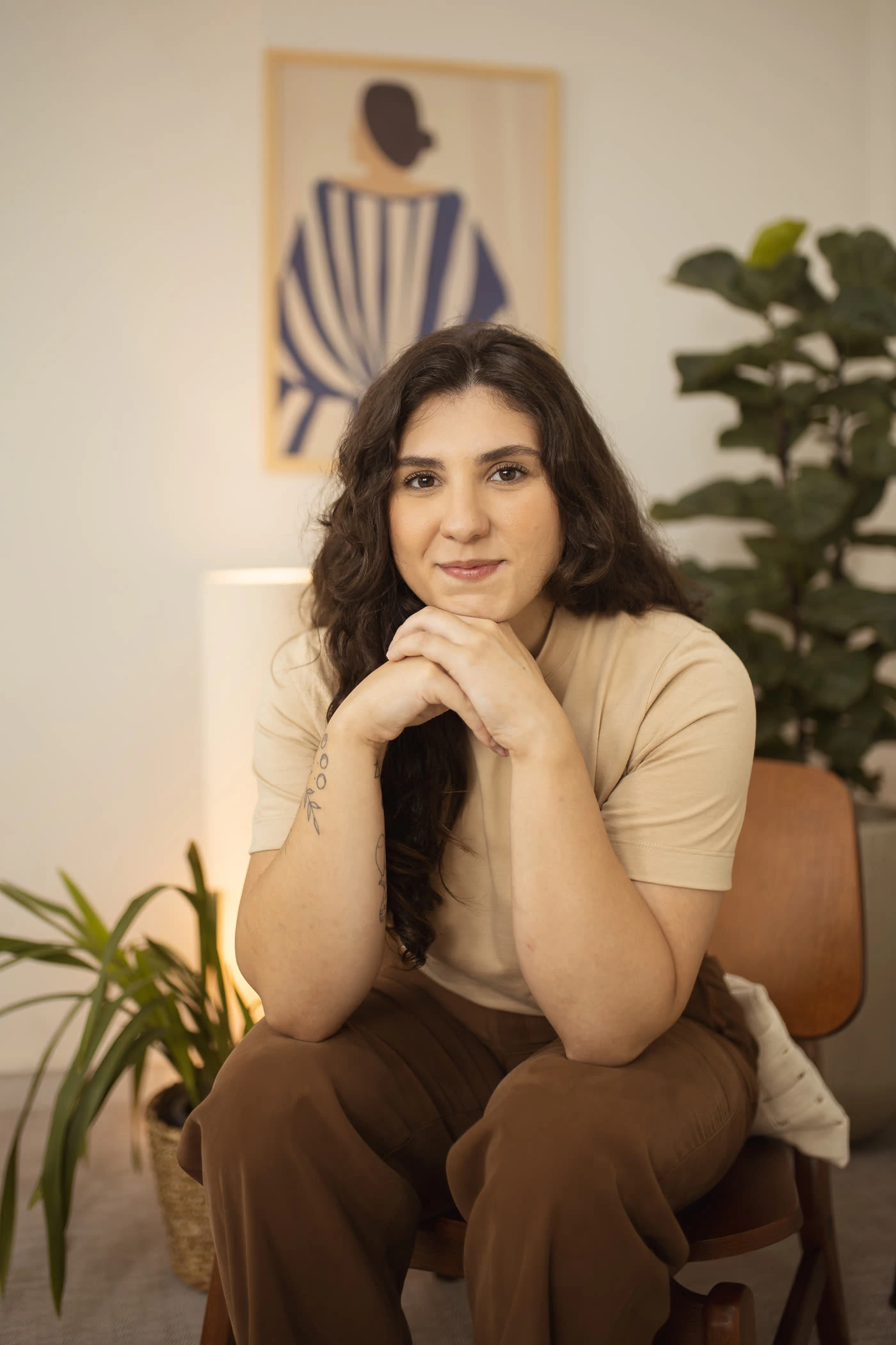 Ana Marques, psicóloga, sentada em uma cadeira de madeira com as mãos apoiadas sob o queixo